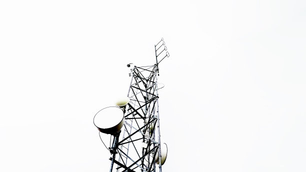 低角度的电信和无线电天线塔对白色多云的天空图片下载