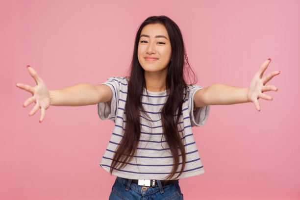 免费的拥抱!可爱友好的女孩肖像与深色头发条纹t恤展开她的双手广泛拥抱图片下载