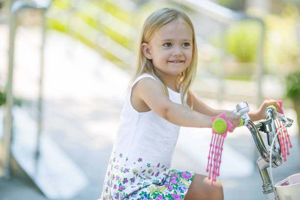 一个5-7岁的金发女孩戴着一顶帽子骑着一辆儿童自行车图片下载