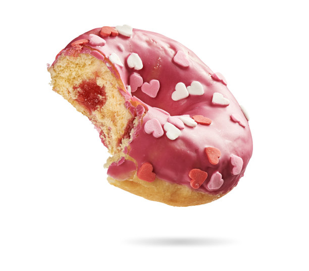 被咬过的草莓甜甜圈上点缀着五颜六色的心形，点缀在白色的蛋糕上图片下载