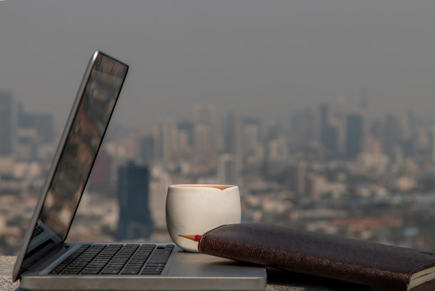 带有笔记本电脑、果汁杯和铅笔的工作区与模糊的城市景观图片下载