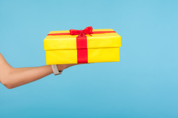 手握大黄色礼盒的特写，祝贺和问候的概念，给奖金，惊喜的生日图片下载