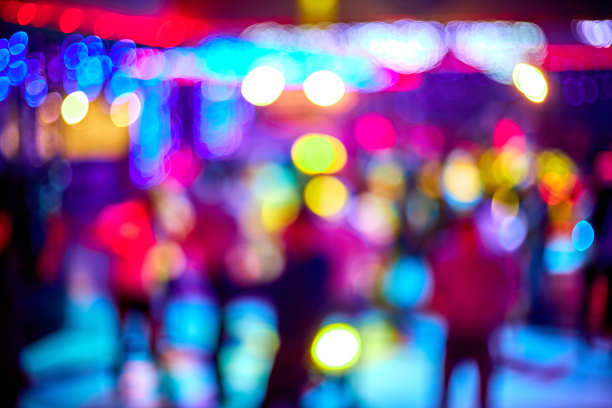 人们跳舞，唱歌，娱乐和放松在夜总会模糊的背景。闪烁的灯光美丽模糊的灯光在舞池放松晚上在俱乐部图片下载