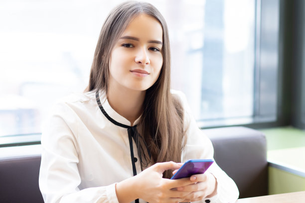 女学生在咖啡馆里拿着智能手机，微笑图片下载
