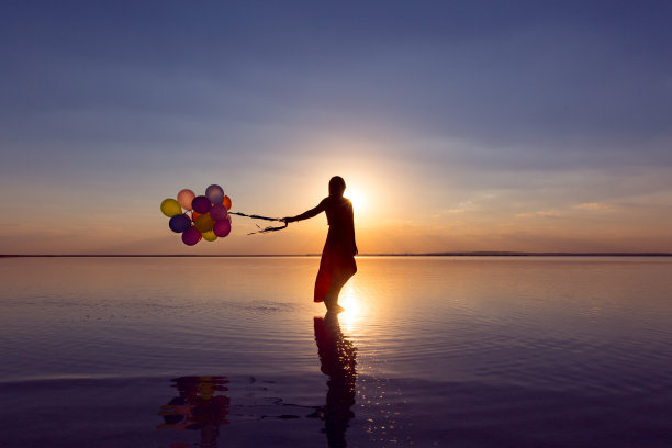 快乐的年轻女子玩彩色气球跑图片下载