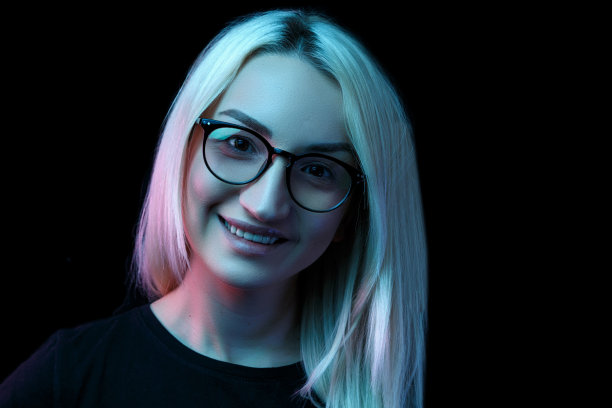 微笑的年轻白种人美丽的金发女人戴着眼镜。特写肖像在霓虹灯图片下载