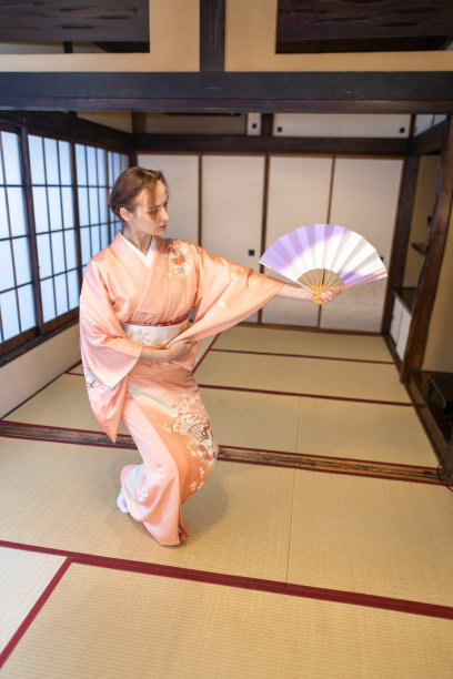 在榻榻米房间里，穿着和服跳舞的俄罗斯女人用折扇图片下载