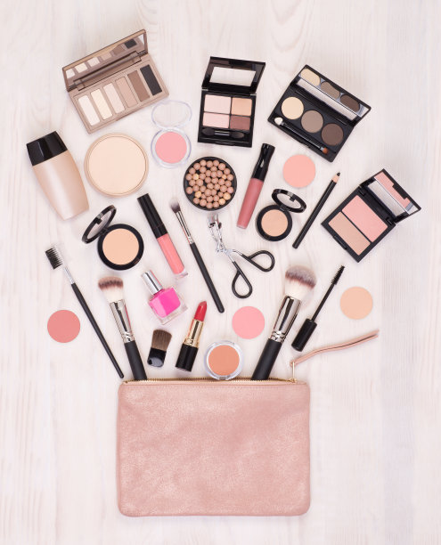 化妆化妆品和配件和一个开放的袋子上的白色木制背景图片下载