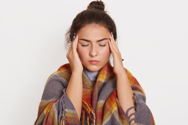 不健康的女人在白色背景下摆姿势的摄影棚照片，深色头发的皱眉女人闭着眼睛站着，触摸太阳穴，患有头痛，感到不适，冠状病毒图片下载