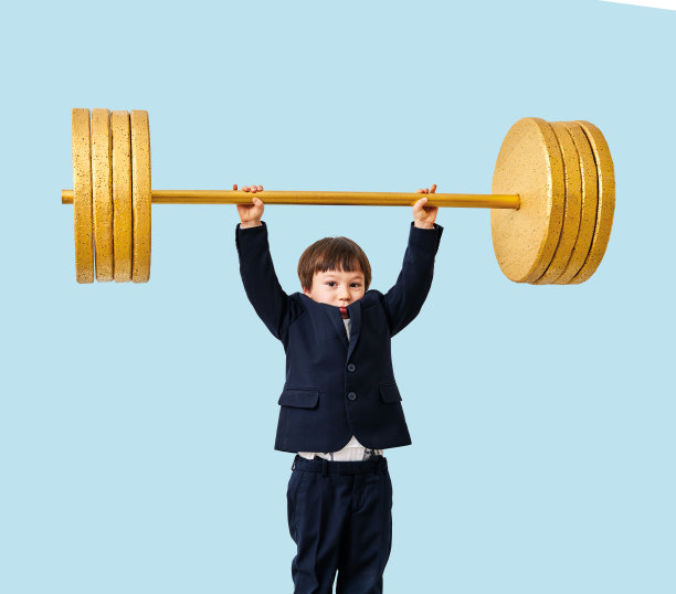 可爱的孩子举起金色的杠铃在蓝色柔和的背景。他是一个有决心和成功的孩子。图片下载