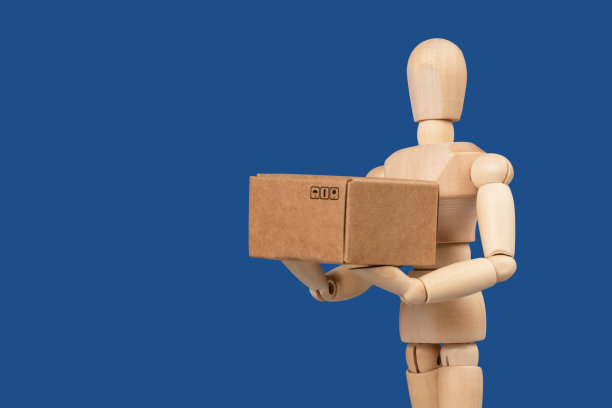 玩具男，快递员手里拿着一个纸箱。蓝色经典的背景。送货及航运服务概念。图片下载