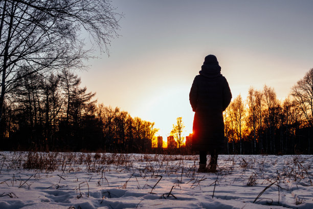冬季，站在夕阳逆光下雪地里的女性轮廓图片下载