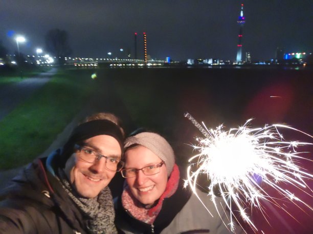 一对年轻夫妇在莱茵河上庆祝新年，身后是Düsseldorf的地平线图片下载