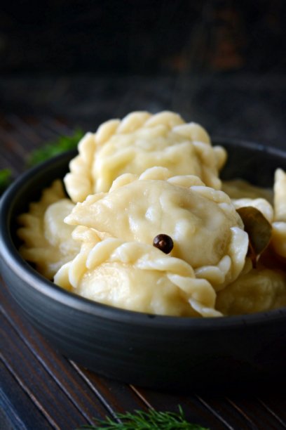 土豆饺子，香草，香料和黄油，一个陶瓷碗在黑暗的背景。Varenyky, vareniki, pierogi，火锅包馅。图片下载