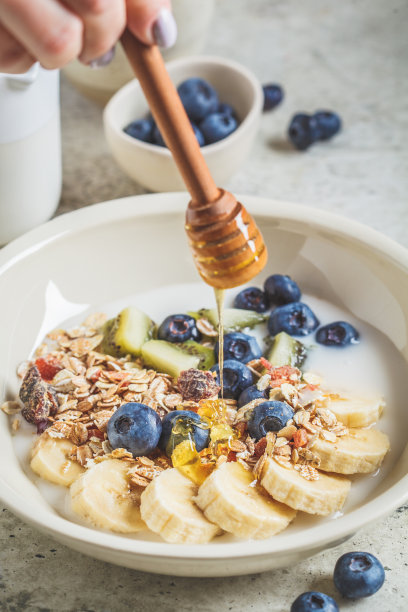 白碗，灰色背景，配酸奶、水果和蜂蜜的什锦麦片。图片下载