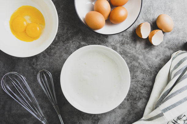 用打蛋器打白鸡蛋，放在调色板中。俯视图女人的手搅拌鸡蛋，烹饪糕点。图片下载