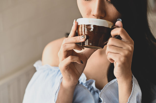 年轻漂亮的女孩在客厅里手捧咖啡杯的照片，放松时光概念图片下载