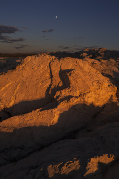 许多棱角分明的灰色石头在夕阳的照射下闪闪发光。蓝色夜空中的月亮和星星。蒙古旅游照片。图片下载