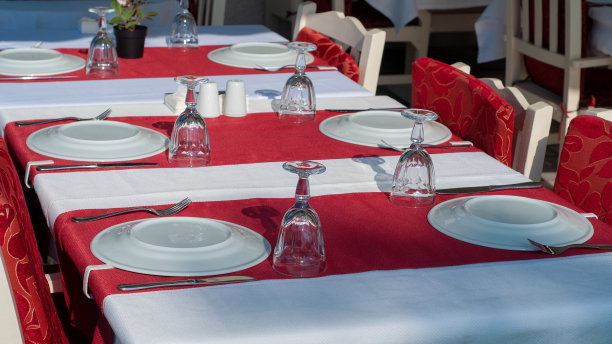 靠近海边的咖啡馆里的一张桌子。红色的桌布，白色的餐巾和干净的盘子。图片下载