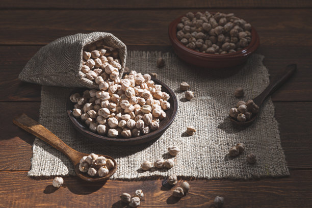 把鹰嘴豆撒在木盘子上，木勺子放在木底座上。图片下载