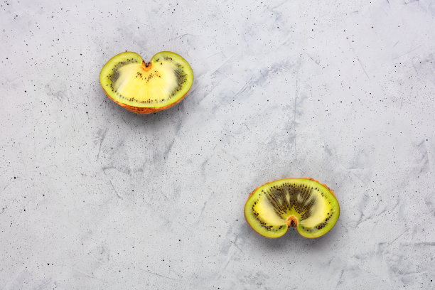 丑陋的绿色猕猴桃在灰色混凝土背景在一个切割形式。顶视图,特写。图片下载