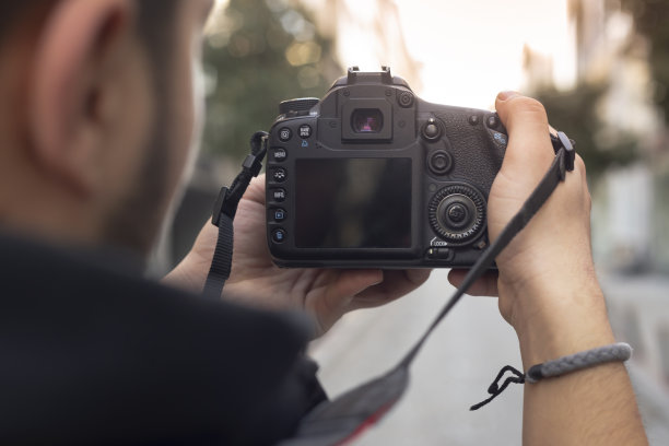 年轻的摄影师在街上看着他的照片图片下载