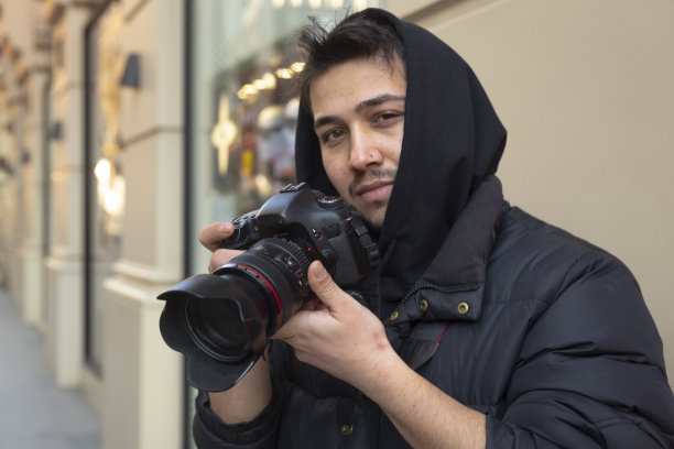 年轻的摄影师在城市的街道上拍照图片下载