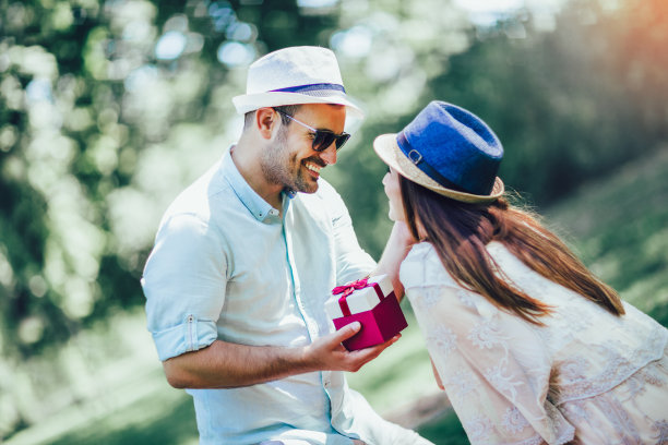 一个年轻人在室外给一个年轻的女孩礼物。图片下载