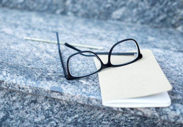桌子上放着一副视力眼镜，还有一本笔记本和一支铅笔。经营理念图片下载