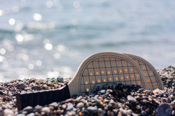 沙滩网球游戏设置，木制球拍的背景可拆卸海滩。图片下载