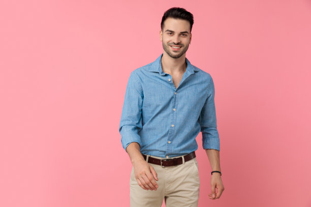 快乐的年轻男人在粉色背景上微笑行走图片下载
