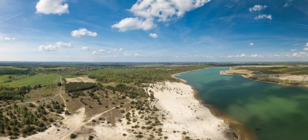 一个天线，左边是一个小村庄，右边是一个湖，地平线上是风力涡轮机。图片下载