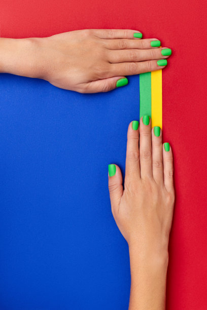 绿色指甲的女性双手在彩色背景上特写图片下载