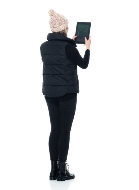 白人女性无袖站在白色背景前，穿着靴子，使用数码平板电脑图片下载