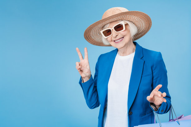 成熟的女人在享受好的购物袋在双手孤立的蓝色背景图片下载