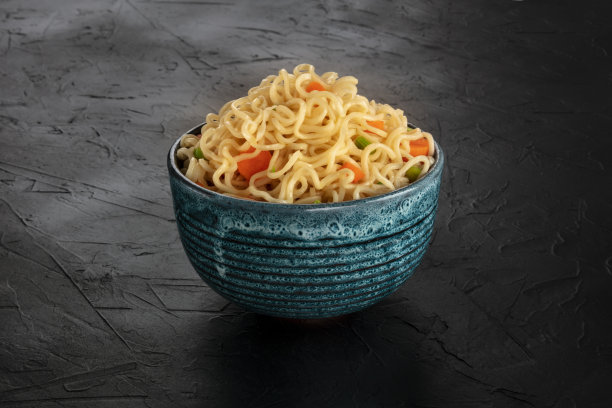 胡萝卜和大葱的方便面，黑色背景上的一碗蔬菜荞麦面图片下载