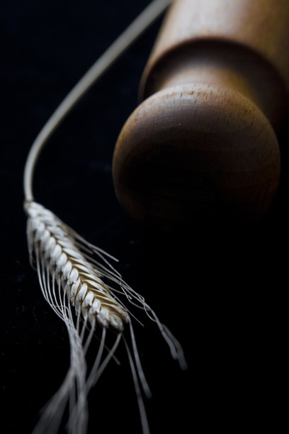 金色的麦穗和木制的擀面杖孤立在黑色的背景上。图片下载