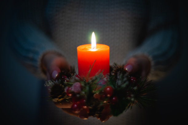 红色圣诞蜡烛和女性手中的花环图片下载