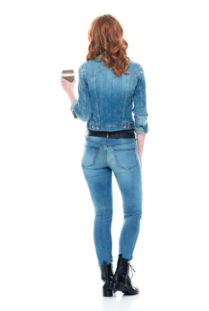 白人女性穿着靴子，拿着咖啡杯站在白色背景前图片下载