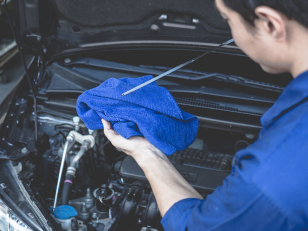 在汽车修理厂工作的汽车修理工。维修服务。亚洲人检查油的水平图片下载