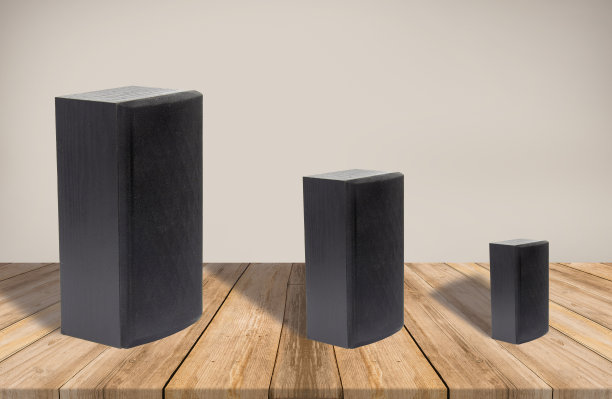 一个工作室的镜头，两个大小不一的黑色扬声器被隔离在一个空房间里，背景是木地板和米黄色的墙壁。图片下载