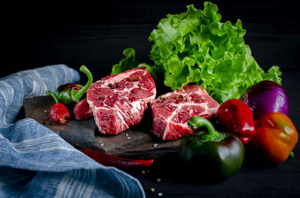 肉的概念。肉排已经准备好了，蔬菜摆在桌上图片下载