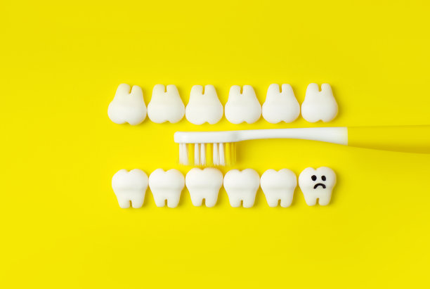 牙刷刷牙。概念与黄色牙刷，牙齿模型与一个悲伤的牙齿(龋齿)。图片下载
