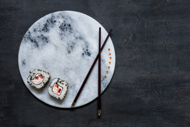 日本蟹黄慕斯寿司与红色鱼子酱在大理石石板与筷子。俯视图，靠近黑色混凝土背景图片下载