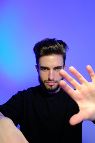 在时尚霓虹灯下的工作室里摆姿势的年轻英俊模特，鲜艳的色彩，明亮的光效，迪斯科风格。图片下载