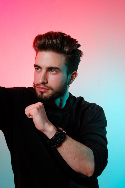 在时尚霓虹灯下的工作室里摆姿势的年轻英俊模特，鲜艳的色彩，明亮的光效，迪斯科风格。图片下载