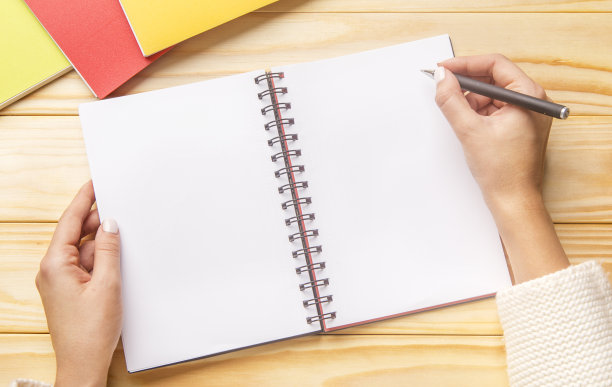女人在木制桌上的螺旋笔记本上绘画图片下载