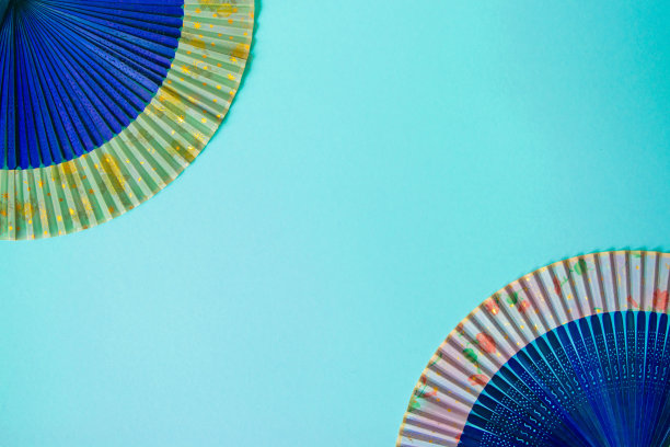 海军蓝女性手扇子的特写，以淡蓝色纸为背景。图片下载
