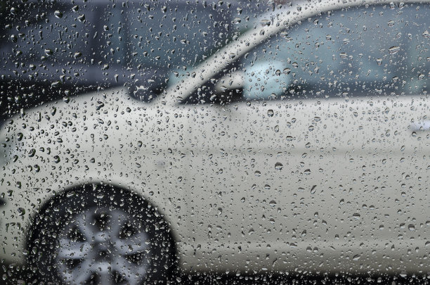 雨点打在玻璃上，有一辆汽车的轮廓图片下载