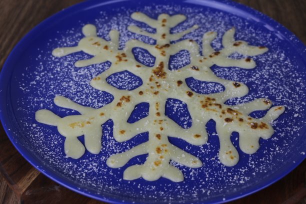 圣诞饼的形象为雪花形状的圣诞儿童的早餐，雪花饼是放在蓝色盘子与干燥的椰子作为雪冬天，概念照片。图片下载